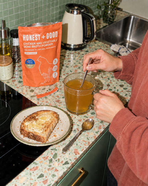 A warm mug of Honest + Good Chicken + Vegetable Bone Broth with toast