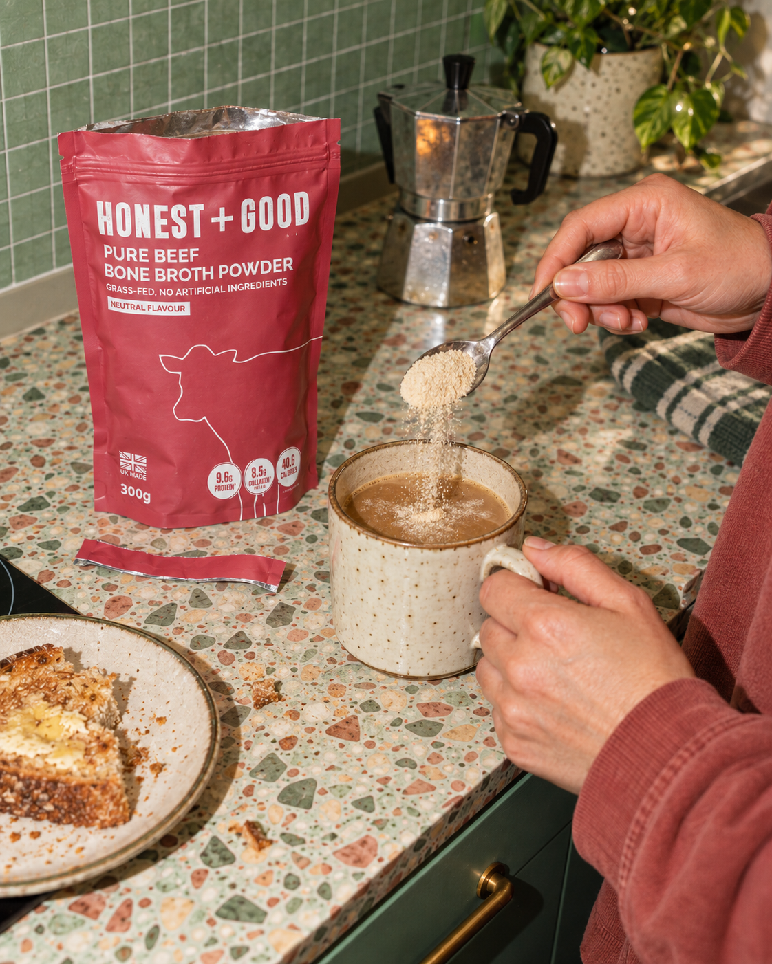 Stirring a spoonful of Honest + Good Pure Beef Bone Broth Powder into a morning coffee