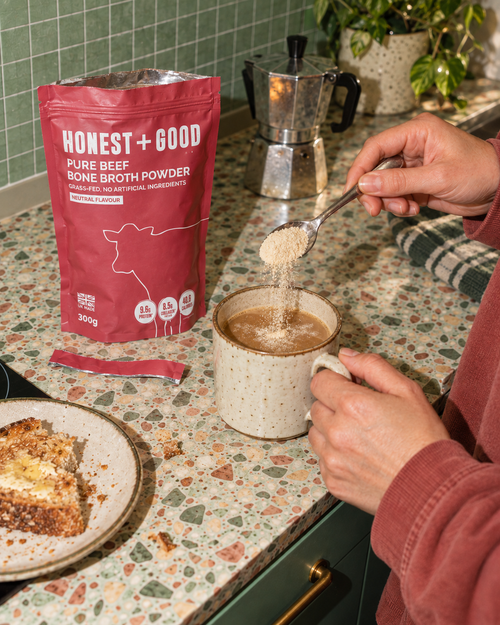 Stirring a spoonful of Honest + Good Pure Beef Bone Broth Powder into a morning coffee