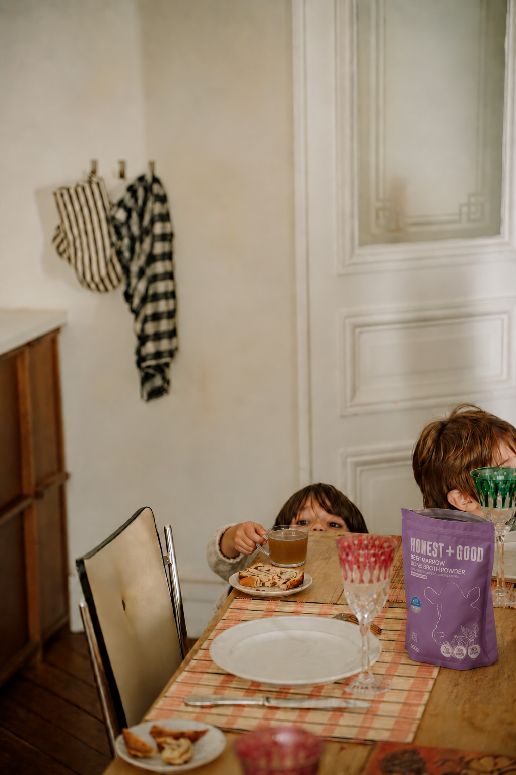 A family dinner table with a pouch of Honest + Good Beef Marrow Bone Broth Powder